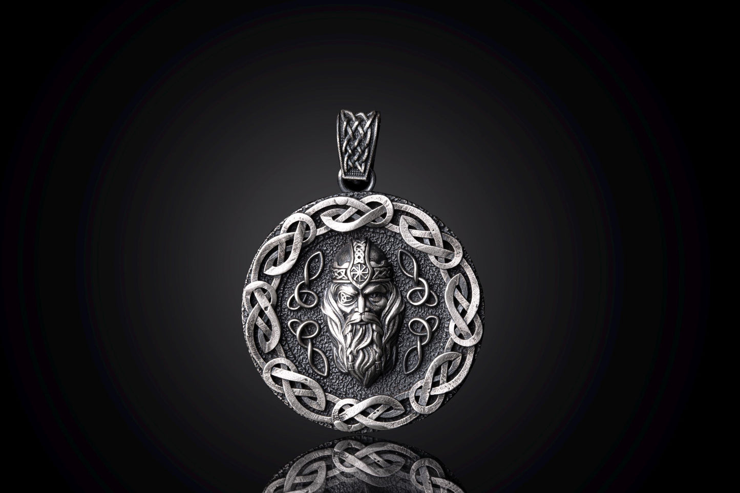 Silver Odin Pendant featuring an intricately detailed Norse god face in the center, surrounded by a decorative Celtic knot border in polished silver, reflecting craftsmanship and mythology.