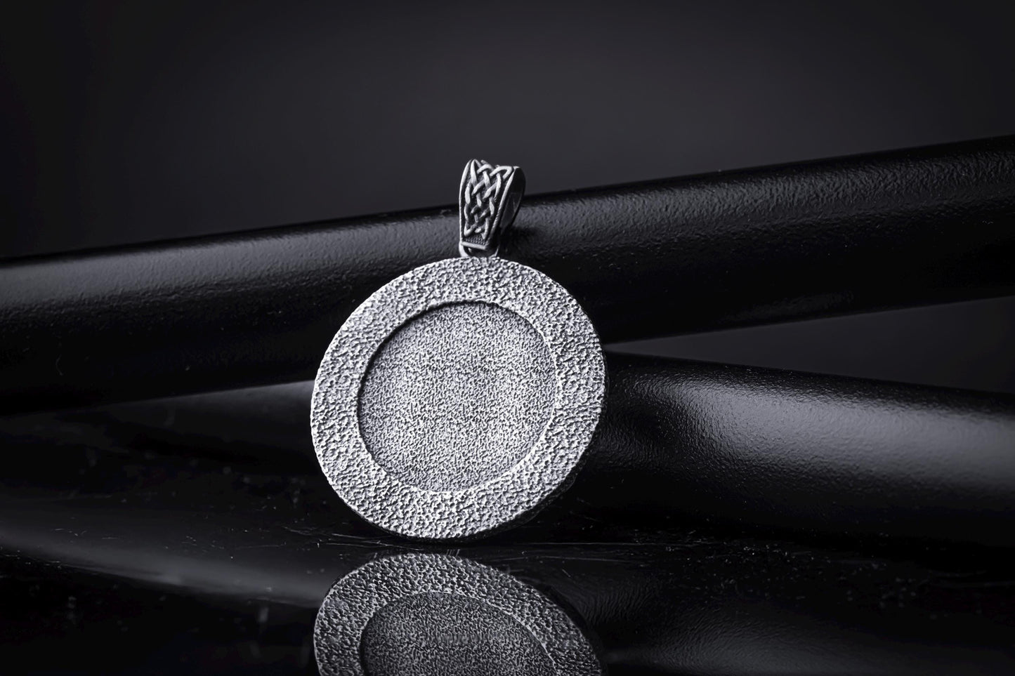 Silver Odin Pendant featuring a textured circular design in polished silver, displayed on a black background with a woven bail detail for chain necklaces.