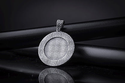 Silver Odin Pendant featuring a textured circular design in polished silver, displayed on a black background with a woven bail detail for chain necklaces.
