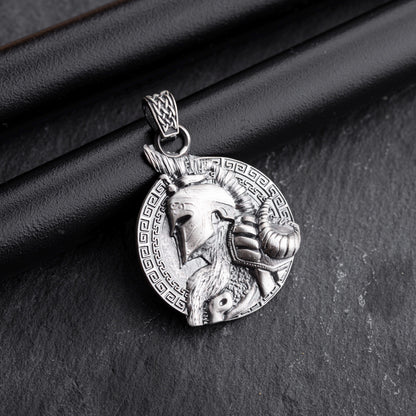 Gladiator Pendant in silver featuring a detailed helmeted warrior profile with a ram's head and intricate braided bail, set against a patterned circular background.
