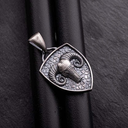 Close-up of an Aries Ram Pendant in silver, featuring a detailed ram's head with curled horns on a textured shield-shaped background with a loop for a chain necklace.