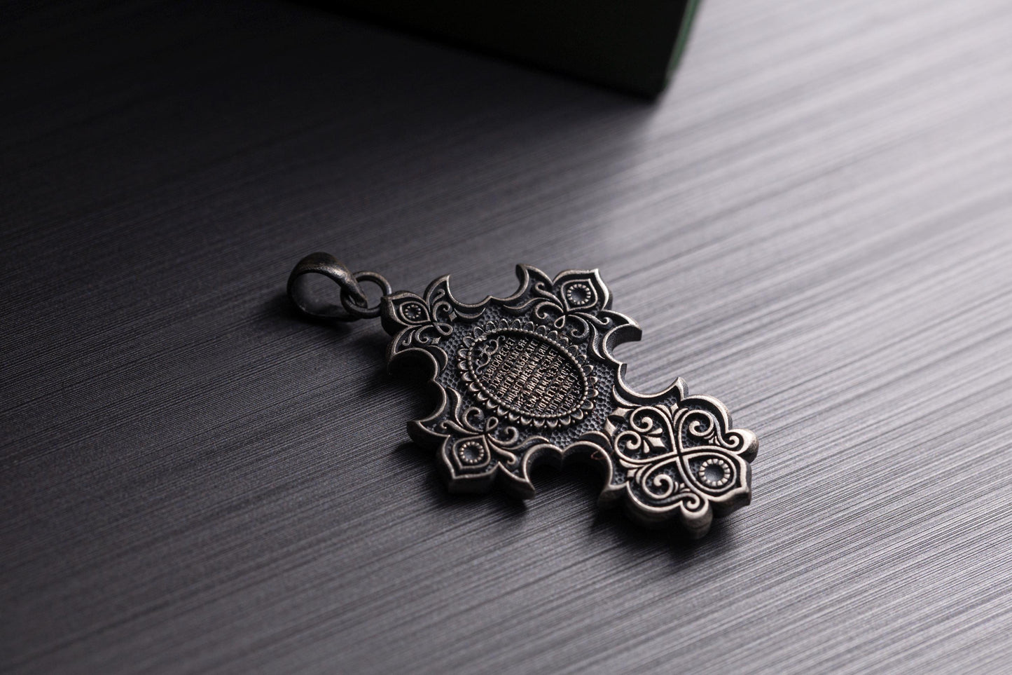 Jesus Crucifix Pendant featuring intricate filigree design in silver tone, lying on a dark textured surface, ideal as a chain necklace accessory.