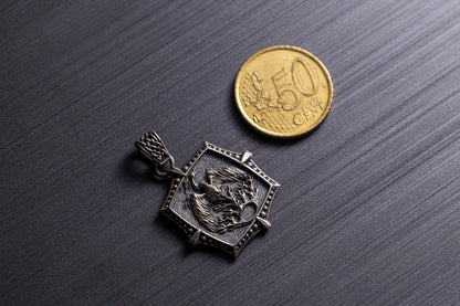 Silver Phoenix Pendant featuring a detailed phoenix design within a hexagonal frame, displayed next to a 50 cent coin for size reference on a dark textured surface.