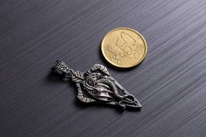 Sterling Silver Dragon Arrowhead Pendant with detailed dragon design displayed next to a 50 cent coin for size reference on a dark textured surface.